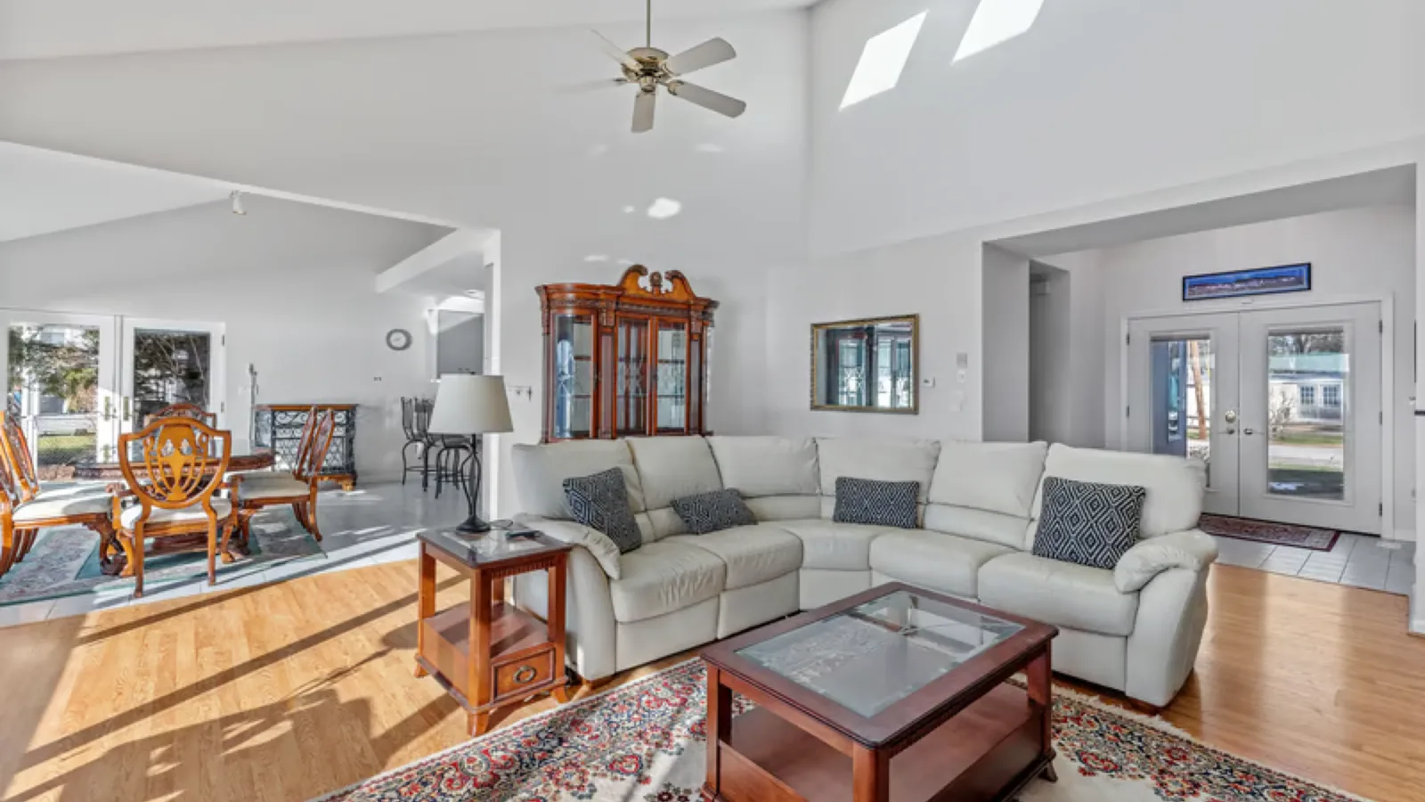 Five blade ceiling fan on a long downrod hanging from a vaulted living room ceiling with skylights