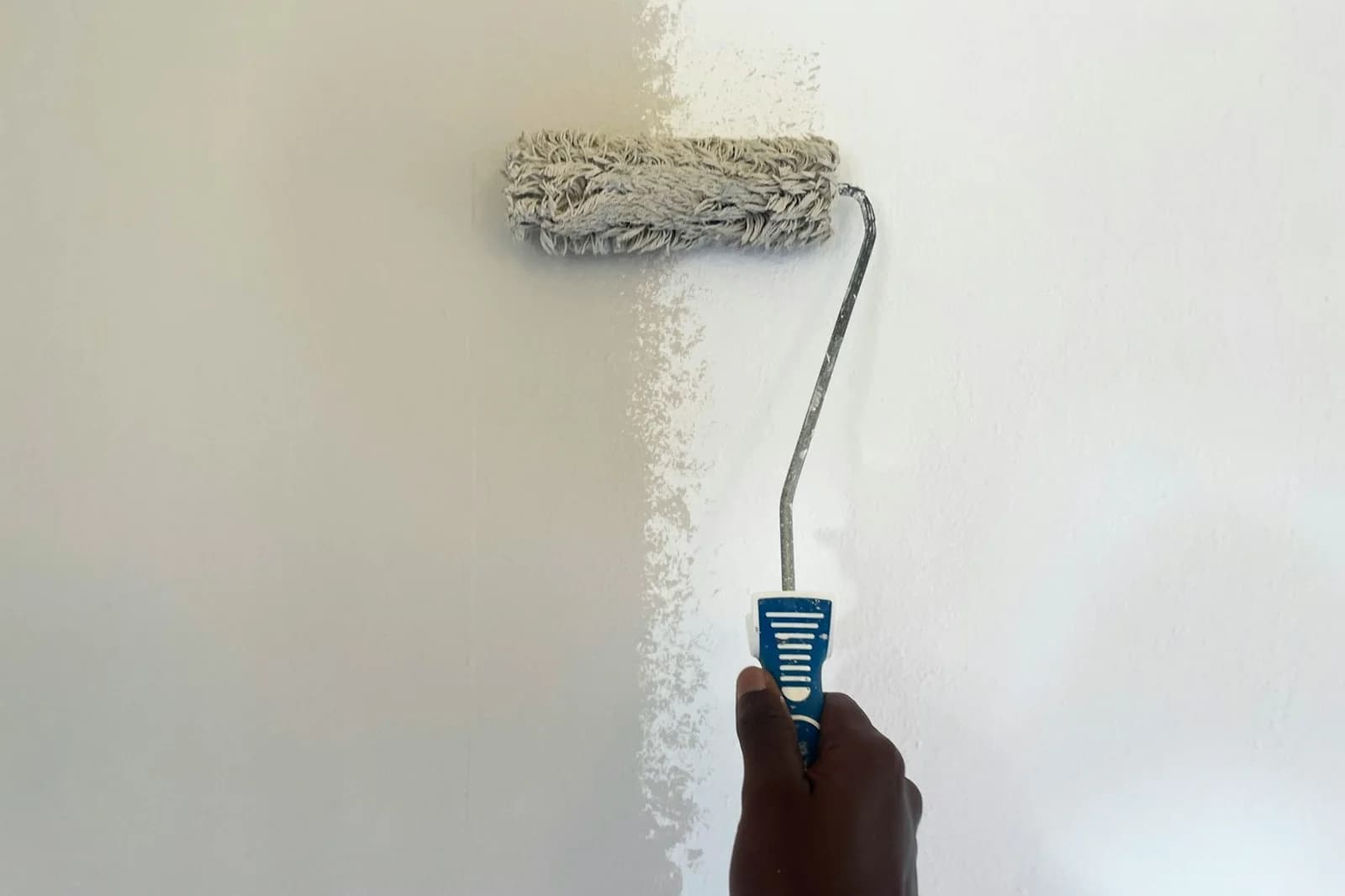 Paint roller applying a fresh coat of warm white paint to an interior wall